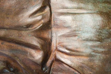 Close-up photo texture of copper or bronze statue material with vertical folds.