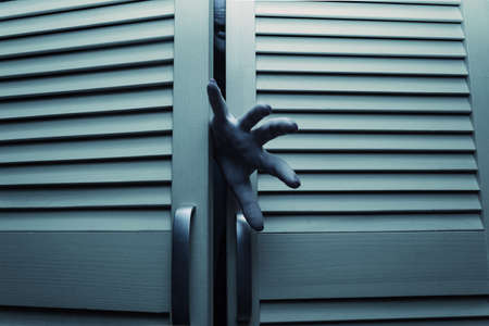 Horror blue toned cupboard doors with scary female monster hands.の写真素材