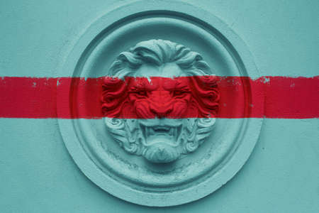 Photo of blue toned lion face bas-relief statue with red grunge painted stripe.の写真素材