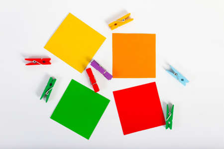Photo of various paper notes laying on table with multicolored pins on white background.