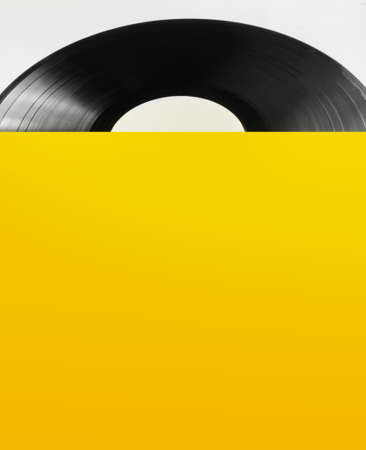 Photo of black vinyl plate with yellow cover laying on white background.