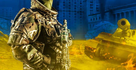 Photo of ukrainian soldier in full body armor holding rifle with scope on devastated and ruined war city background.の写真素材