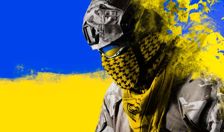 Photo of fully equipped ukrainian military soldier in uniform on national flag background.の写真素材