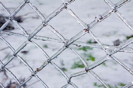 Close up photo of frozen metal fence surface covered in ice texture.の写真素材