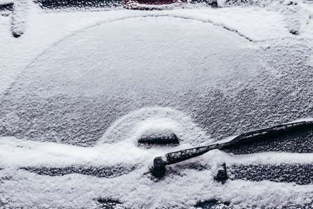 Photo of rear car window with windshield wiper blades covered in snowの写真素材