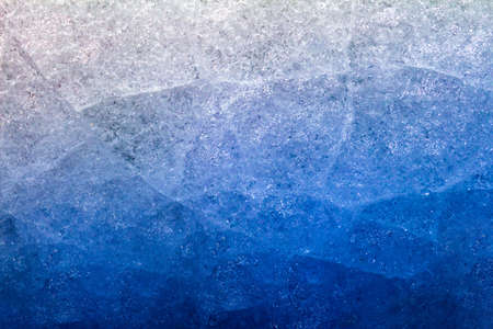 Photo of blue toned gradient frozen cracked ice surface texture.