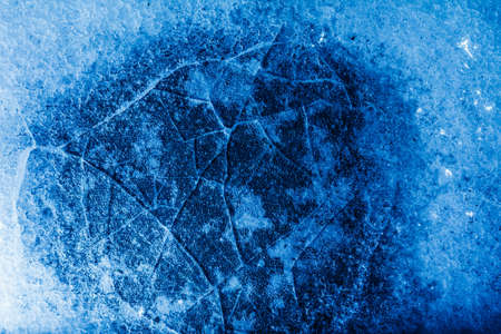 Photo of blue toned frozen cracked ice with snow surface texture.の写真素材