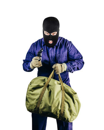 Isolated photo of robber in mask, overalls, gloves, bag and gun standing on white background.