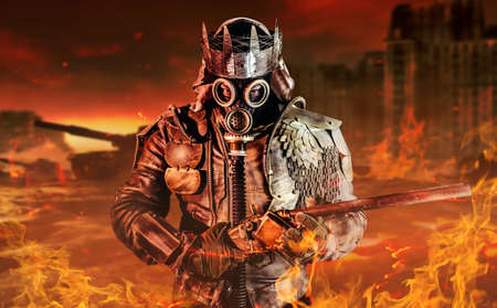 Photo of post apocalyptic warrior with armored outfit jacket and scrap crown standing with rifle on destroyed burning city background.の写真素材