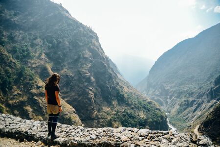 Standing young woman on the hill and looking on mountains. Landscape with happy girl, mountains in...