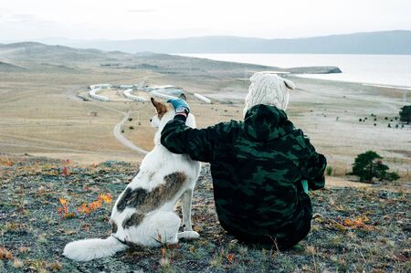 young woman back with dog sitting on the grass in a parkの写真素材