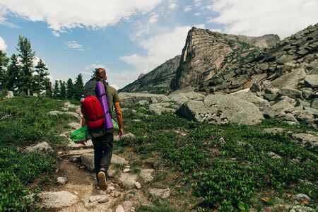 Tourist with a backpack in mountains panorama