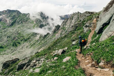 Tourist with a backpack in mountains panoramaの写真素材
