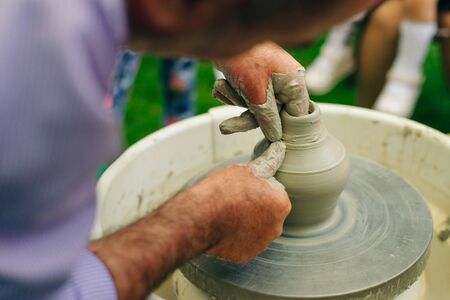 man working on the potter's wheel. Hands sculpts a cup from clay pot. Workshop on modeling on the potter's wheel.の写真素材