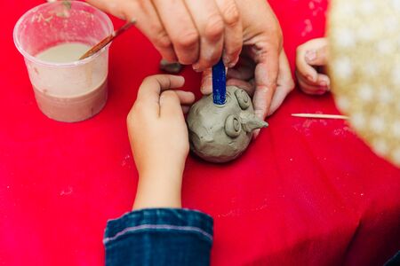 little boy moulds from plasticine on table, Child hands playing with colorful clay, day care close up,の写真素材