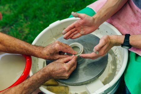 man working on the potter's wheel. Hands sculpts a cup from clay pot. Workshop on modeling on the potter's wheel.の写真素材