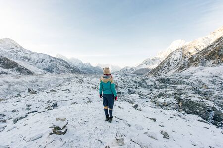 Landscape with girl, high mountains with snowy peaks, path, blue sky in Nepal. Travel.