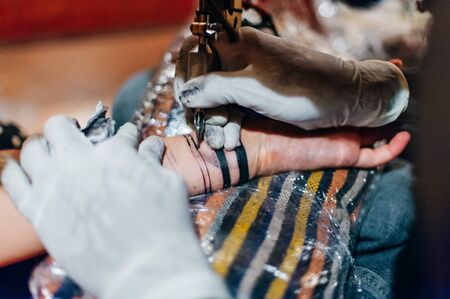 Tattoo artist doing tattoo in tatoo salon.