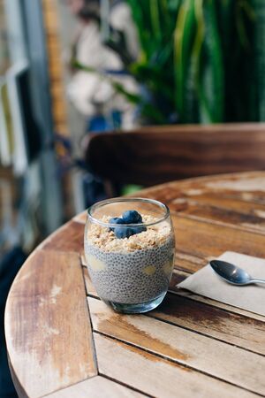 blueberry yogurt parfait with granola, oats and chia seeds in a glass on white wooden tableの写真素材