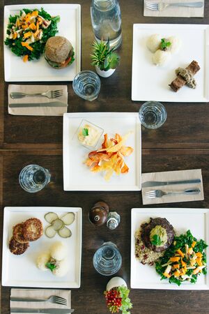 Wooden table set with organic and colorful food for four people in restaurantの写真素材