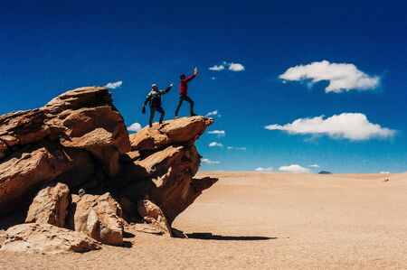 tourists are photographed on rocks in the Uyuni desert, Bolivia - june, 2018.