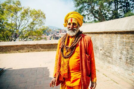 Sadhu man with traditional painted face in Pashupatinath Temple of Kathmandu, Nepal - august, 2019.