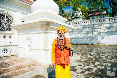 Sadhu man with traditional painted face in Pashupatinath Temple of Kathmandu, Nepal - august, 2019.