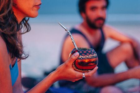 Young woman drinking traditional Argentinian yerba mate tea from a calabash gourd with bombilla stickの写真素材