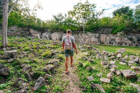 Man walking to Ancient mayan wall with arches with green garden around in Uxmal, Mexico.の写真素材