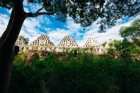 Ancient mayan wall with arches with green garden around in Uxmal, Mexico.の写真素材