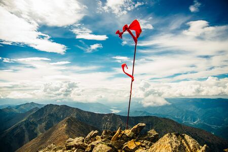 red flag on top of the mountain with blue sky.の写真素材