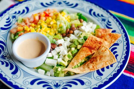 mexican salad with corn, pepper, chips, cheese, avocado and sauce.の写真素材