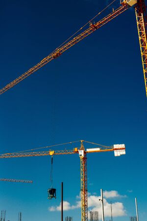 Yellow Industrial Cranes Working on Construction Site Against Blue Sky.