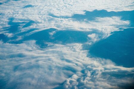 Plane window view of clouds and islands surrounded by sea and airplane wing. Traveling concept.の写真素材