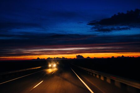 Silhouette of car on bridge in sunset at night.