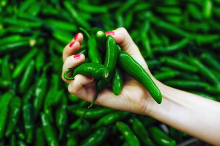 girl's hand holds Mexico Green Chile peppers on the market.の写真素材
