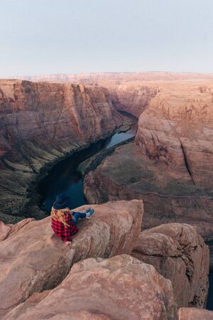 blonde girl sitting Horseshoe Bend in Glen Canyon National Recreation Area in early dawn.の写真素材