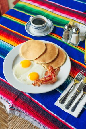 Tasty breakfast with pancakes, fried eggs and bacon on table.の写真素材