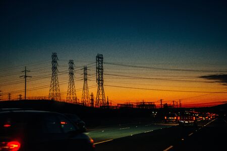 Electric transmission lines against a background of sunset over mountains.
