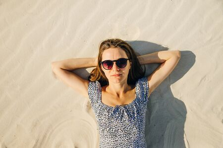 Girl with glasses is relaxing by laying down on the beach. top viewの写真素材