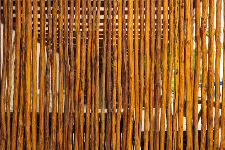 Dark wooden fence of twigs stick texture. Wooden background of pines for designの写真素材