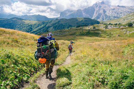 Group hiking in the mountains with large backpacks. Russia.