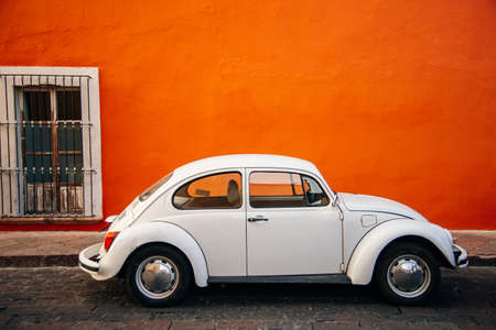 white old Volkswagen near orange wall in mexico.のeditorial素材
