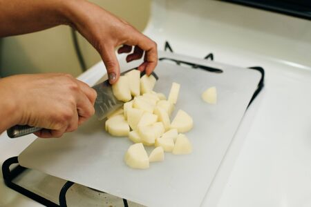woman cook potato slices with a kitchen knife on a cutting board. view from above close-up.の写真素材