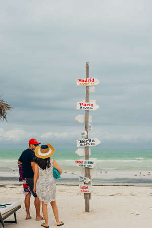 Young travelers on Holbox Island in Mexico with a sign indicating nearby cities and local foodのeditorial素材
