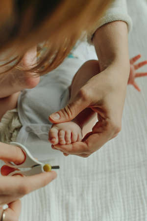 Mather hand holding scissors trimming child toenailの写真素材