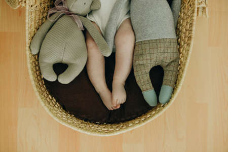 toddler feet beside teddy plush toys in wicker basket.