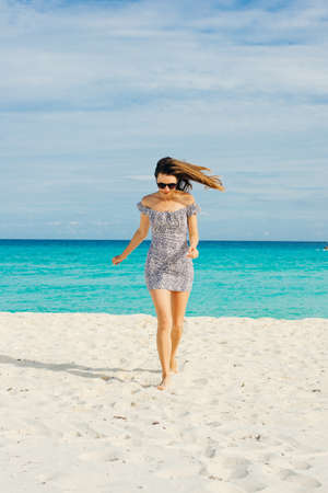 Lonely charming girl looking at the calm sea with wind in her hair in a short dressの写真素材