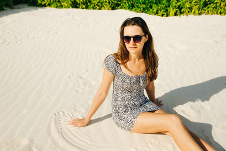 Sensual portrait of a young woman against a background of bushes. Romantic image. A woman lies on the sand.の写真素材