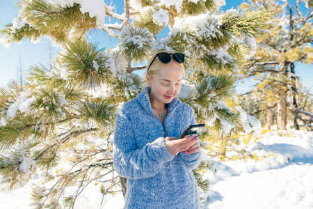 blonde girl writes sms in the winter forestの写真素材